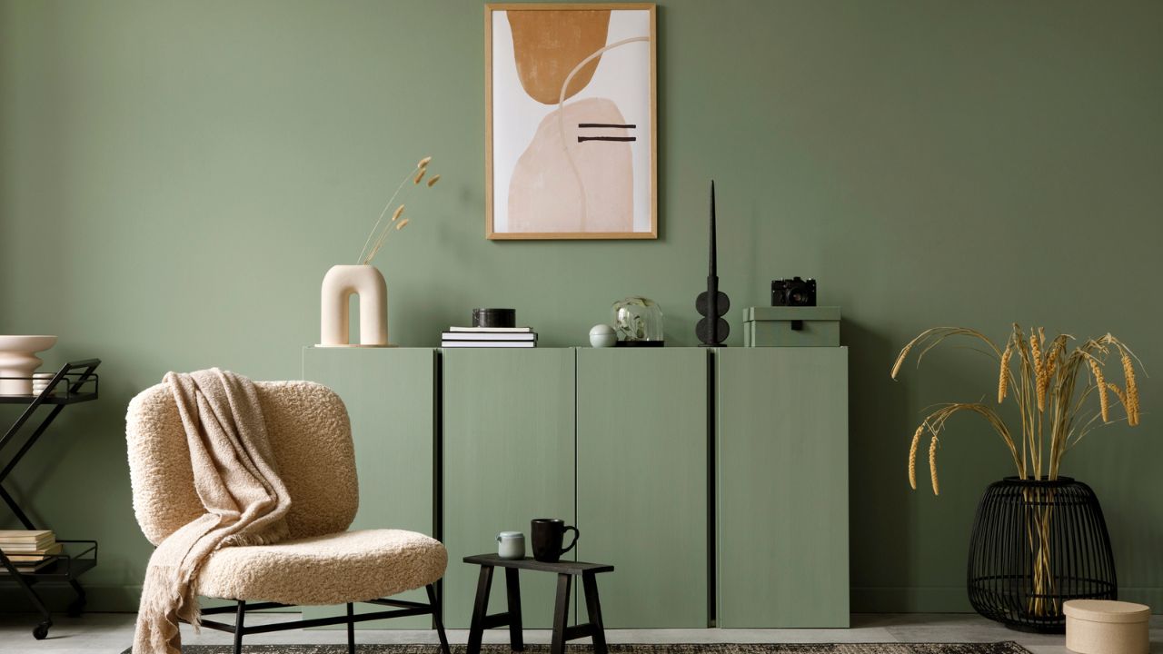 Modern living room corner with green cabinet, abstract art, and decorative plants in a minimalist style.