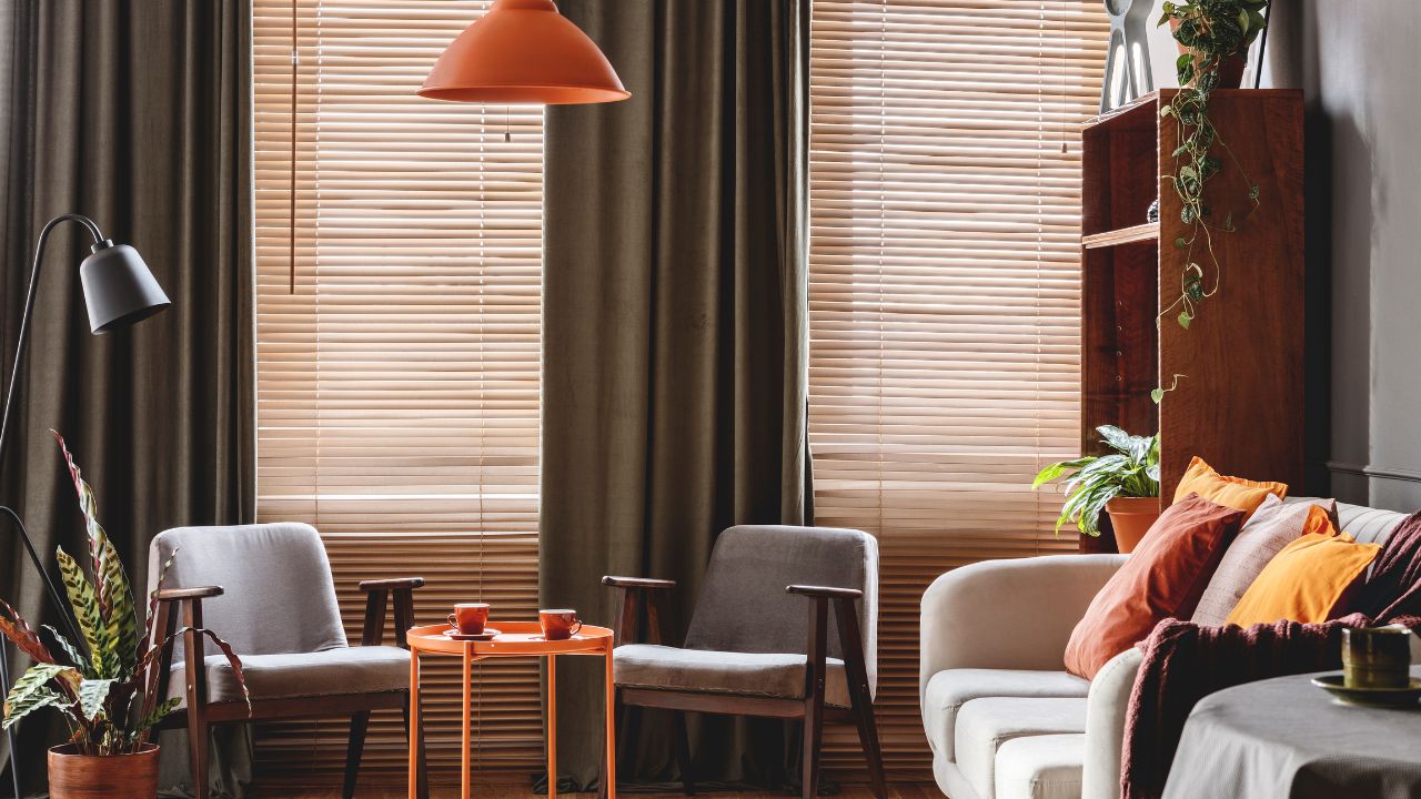 Living room with large window blinds, curtains, and cozy furniture arrangement.