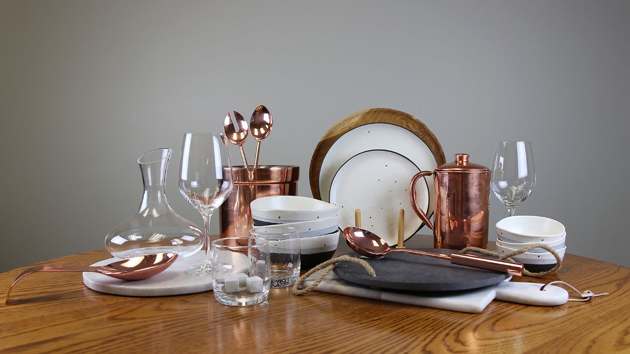 Table setting with rose gold cutlery, flowers, and lace fabric.