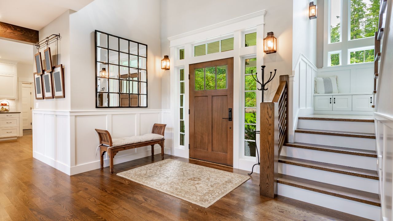 A warm, inviting hallway with hardwood floors and a decorative mirror by the front door.