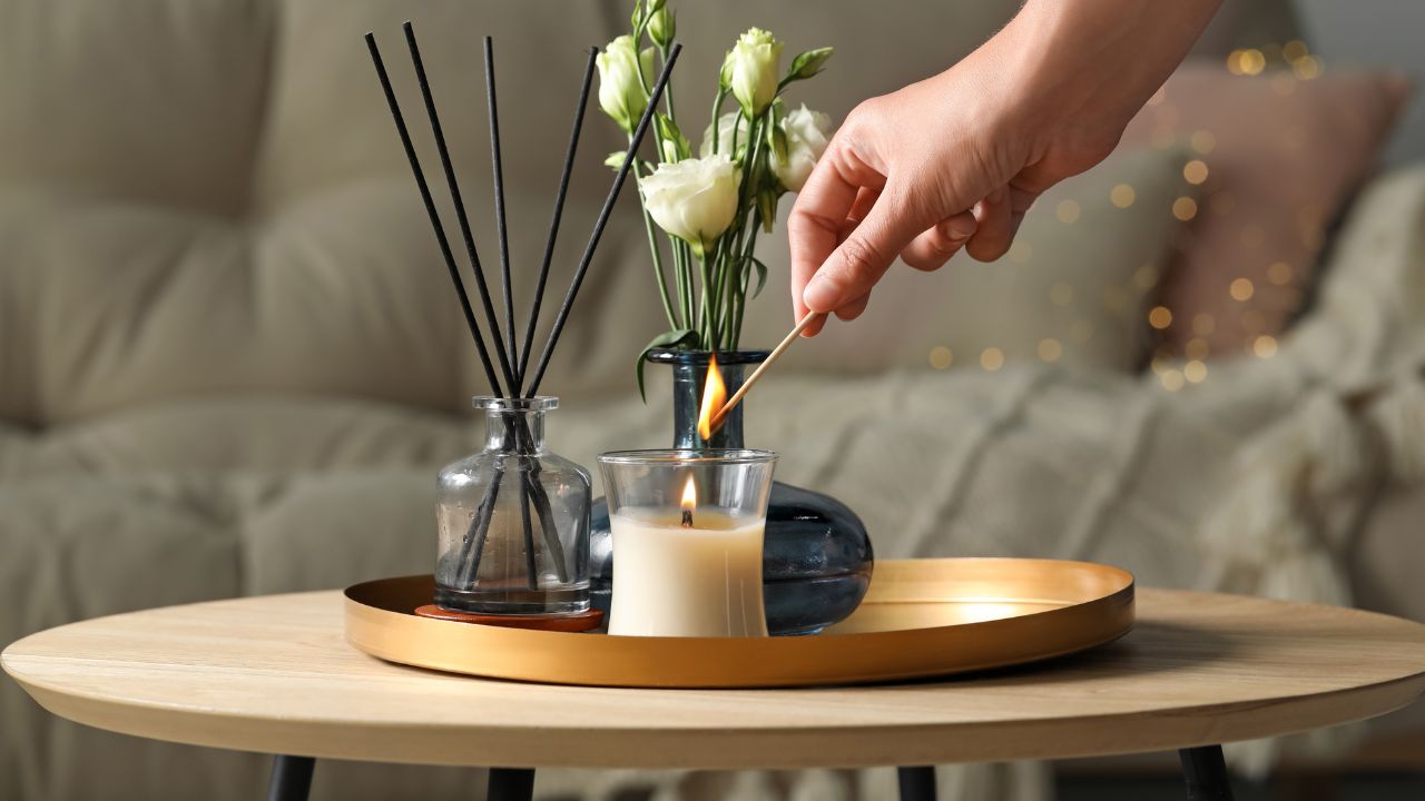 Hand placing a flower in a vase with candles and decorative items.