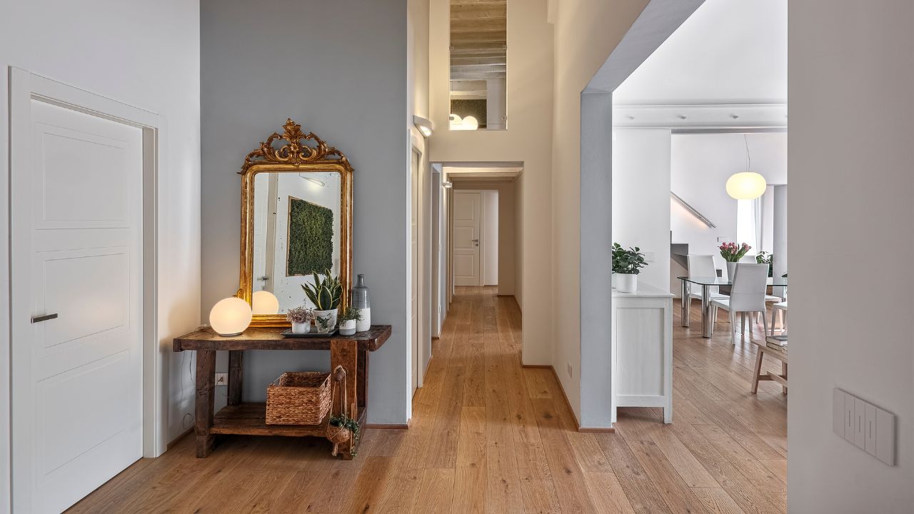 A stylish hallway with a large antique mirror, soft lighting, and decorative plants.