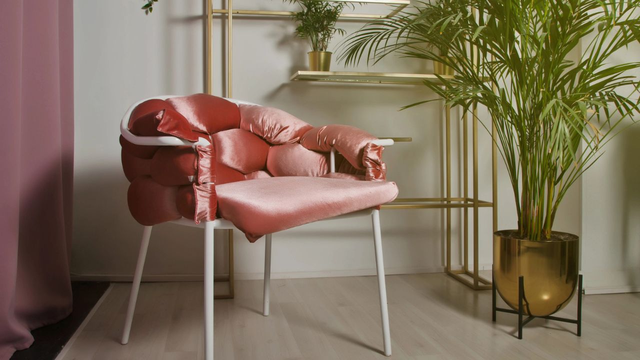 A stylish room with a pink velvet chair, a large potted plant, and elegant decor.