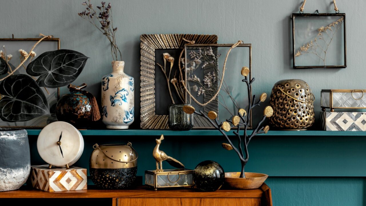 Decorated shelf with various vases and art pieces against a teal wall.