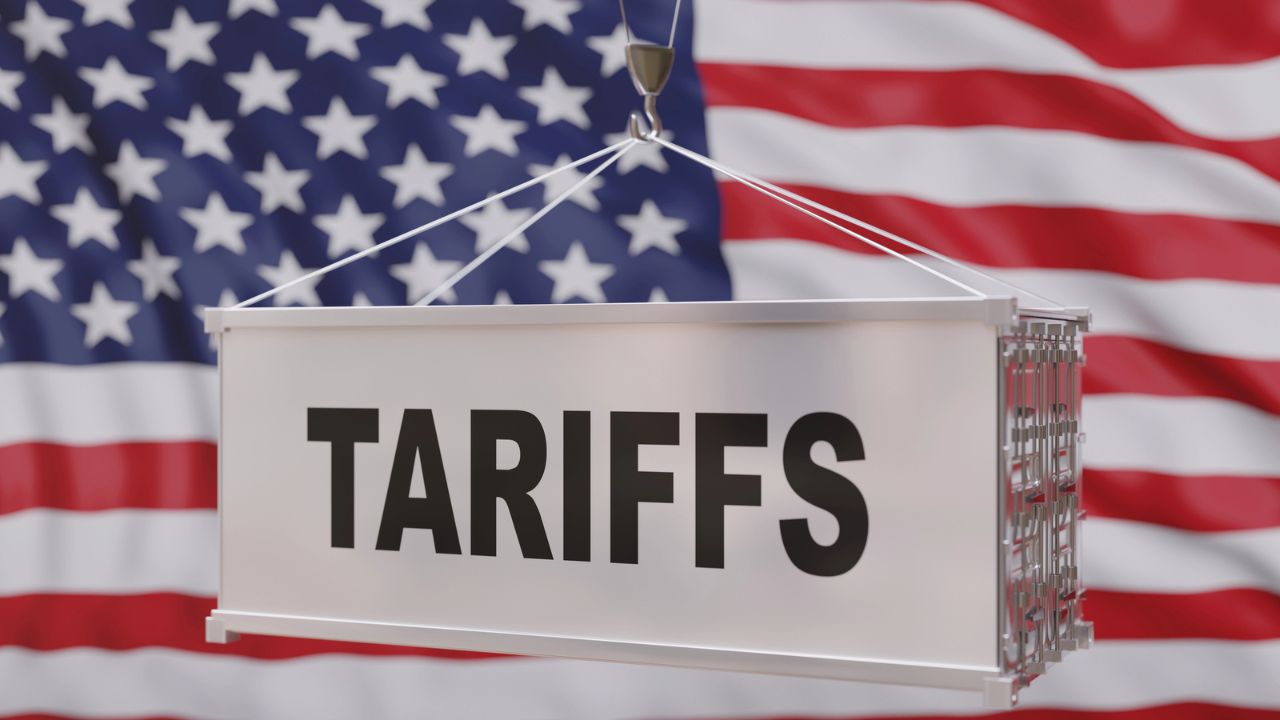 A sign with the word "TARIFFS" in front of an American flag background.
