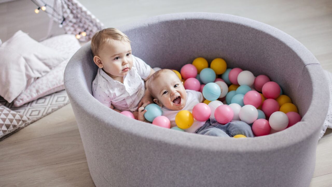 Babies enjoying in a dry pool filled with colorful balls.