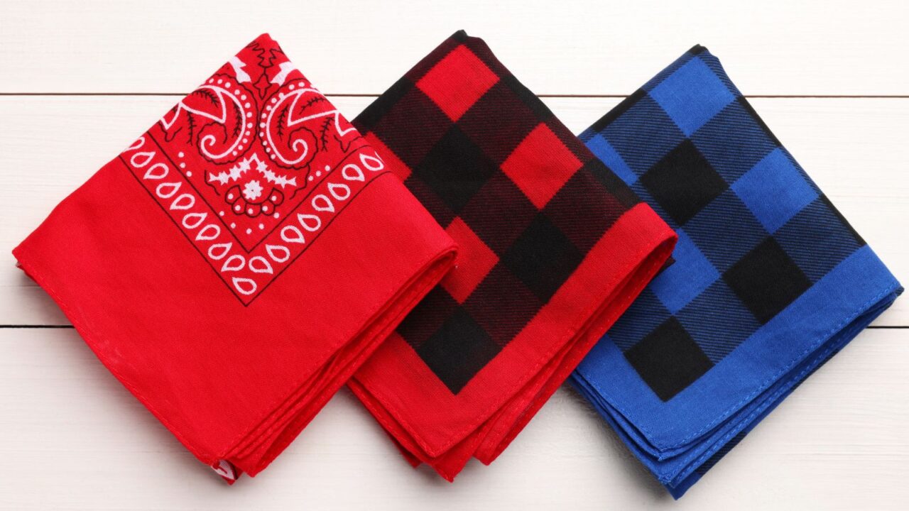 Different bandanas in red and blue placed on a wooden table.