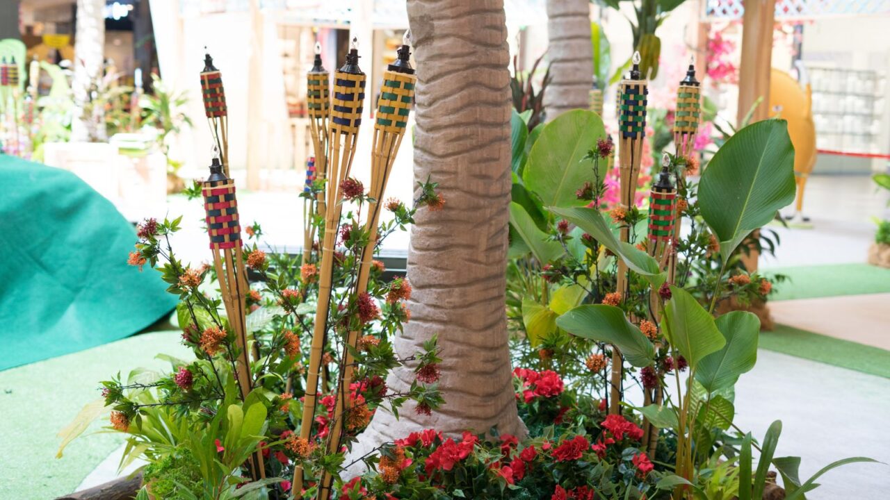 Funky tiki torches and flowers surrounding a tree.