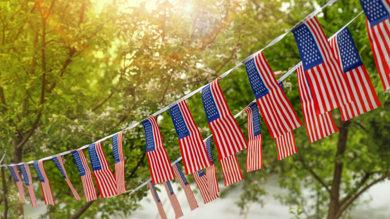 A DIY garland with small flags attached on a white ribbon.