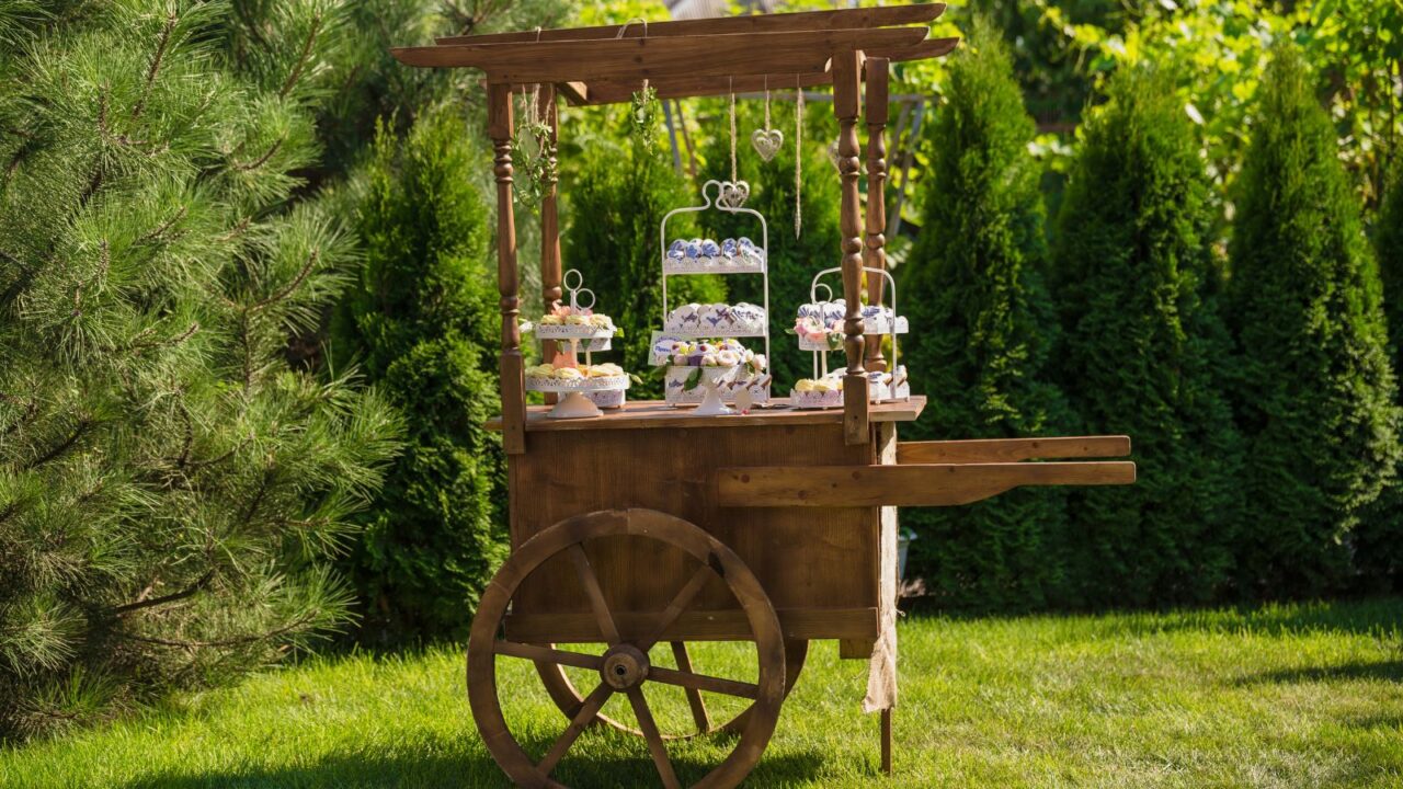 A wooden cart with different sweets in a garden.
