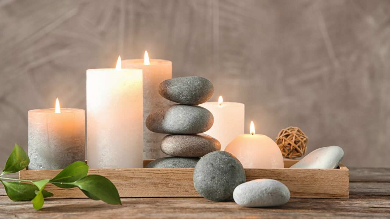 A wooden tray with candles and stones on a wooden surface.