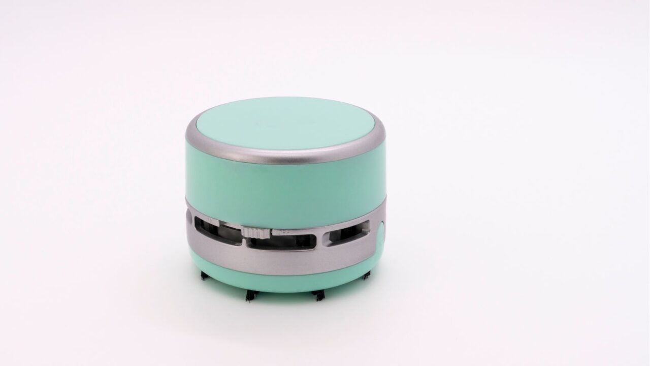 A mini desk vacuum on a white surface.