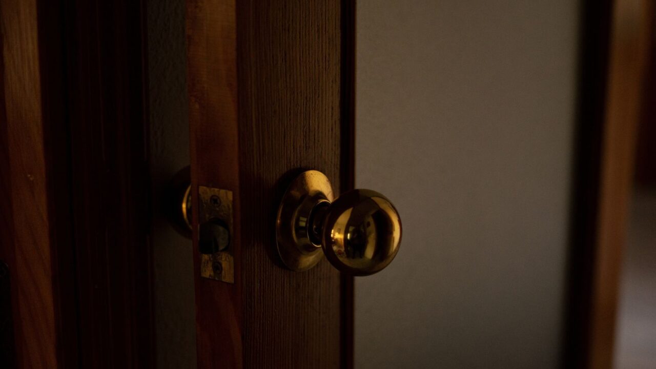 A sleek wooden door with a golden knob.