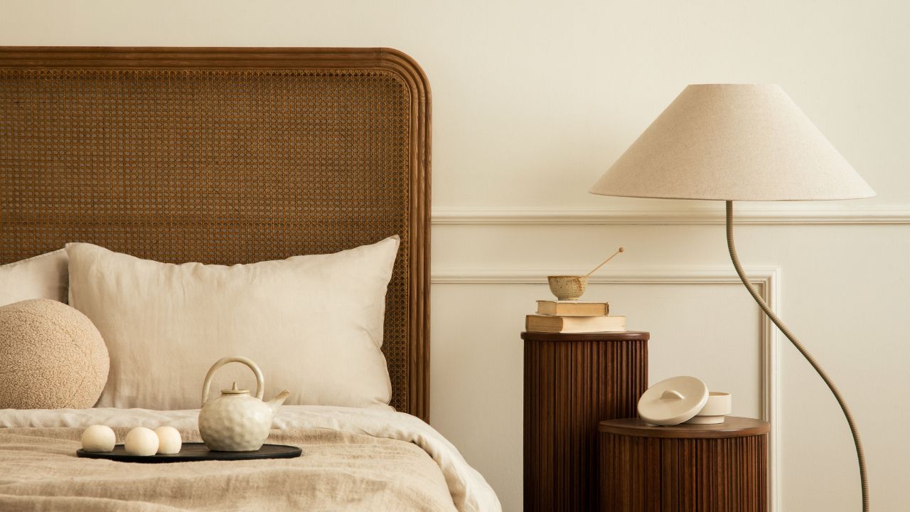A cozy bedroom corner with a wooden headboard, cushion, and tea set on the bed.