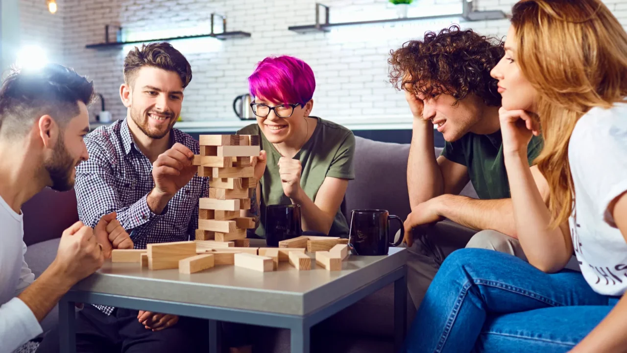 Group of friends sitting around a table and playing Jenga.