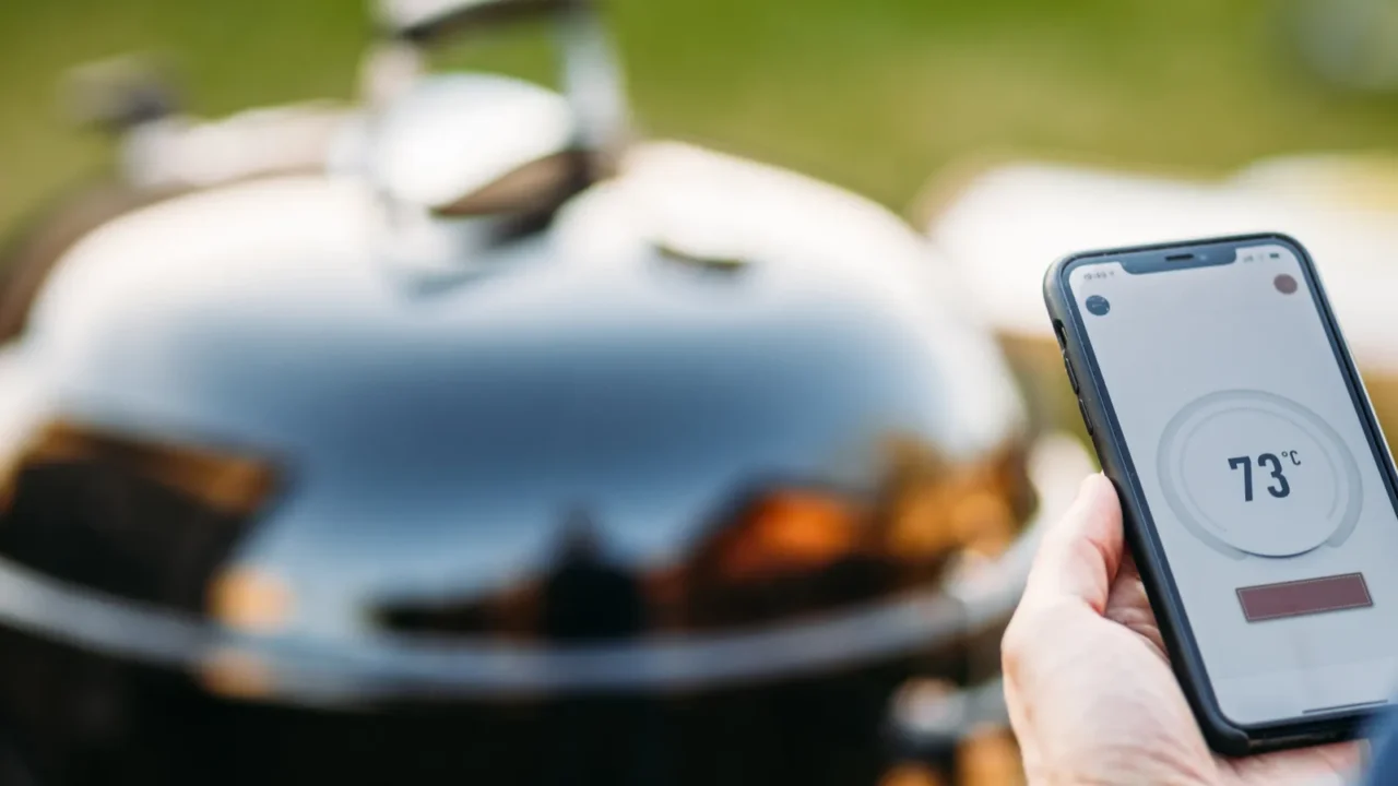 A smartphone displaying temperature from a grill using a smart meat thermometer.