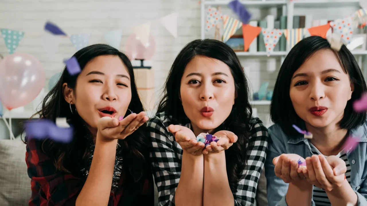 asian cute ladies face camera cheerfully blowing colorful confetti young