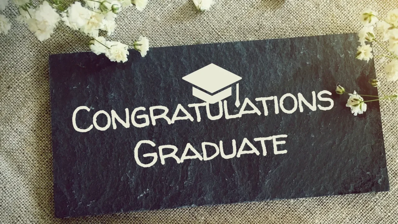 A chalkboard with 'Congratulations Graduate' written on it and flowers around it.