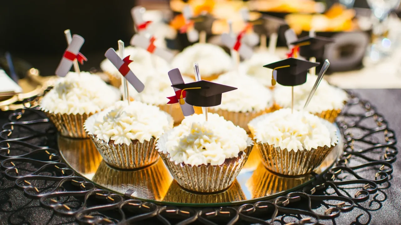 Cupcakes arranged on a beautiful mirrored tray with cute grad party toppers.