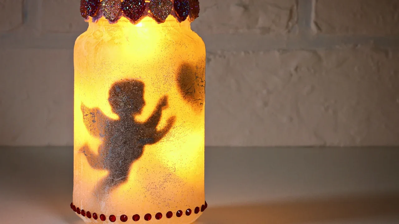 A DIY glass jar candle holder in front of a brick wall.