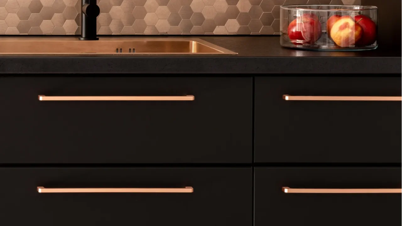 Modern kitchen with black cabinets and copper handles.