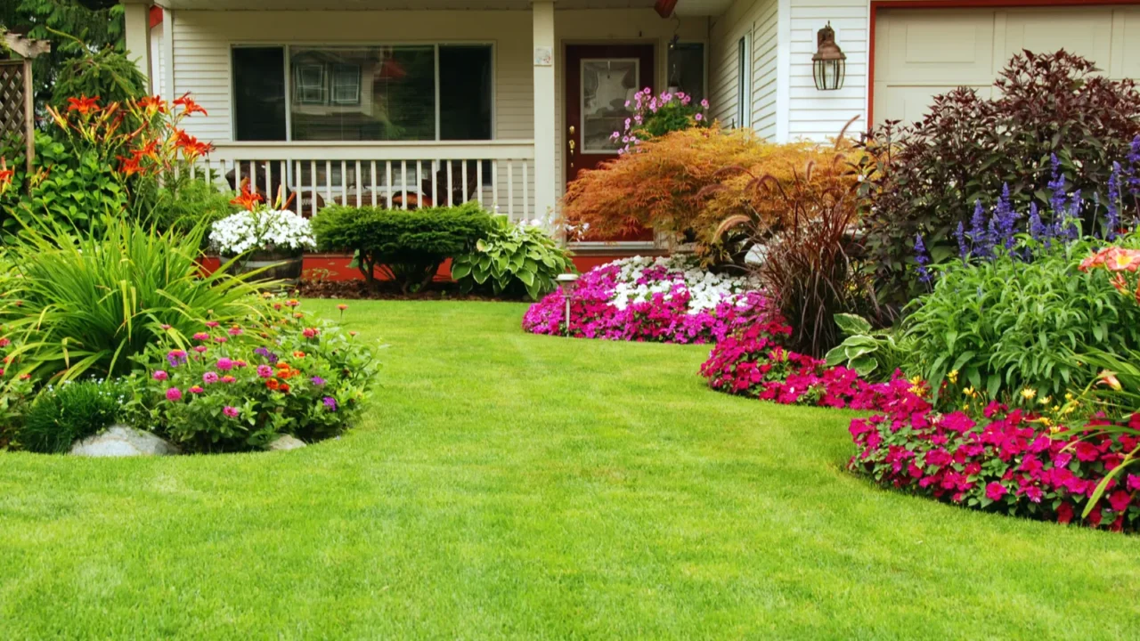 Beautiful front yard with a well-maintained garden, colorful flowers, and a house in the background.