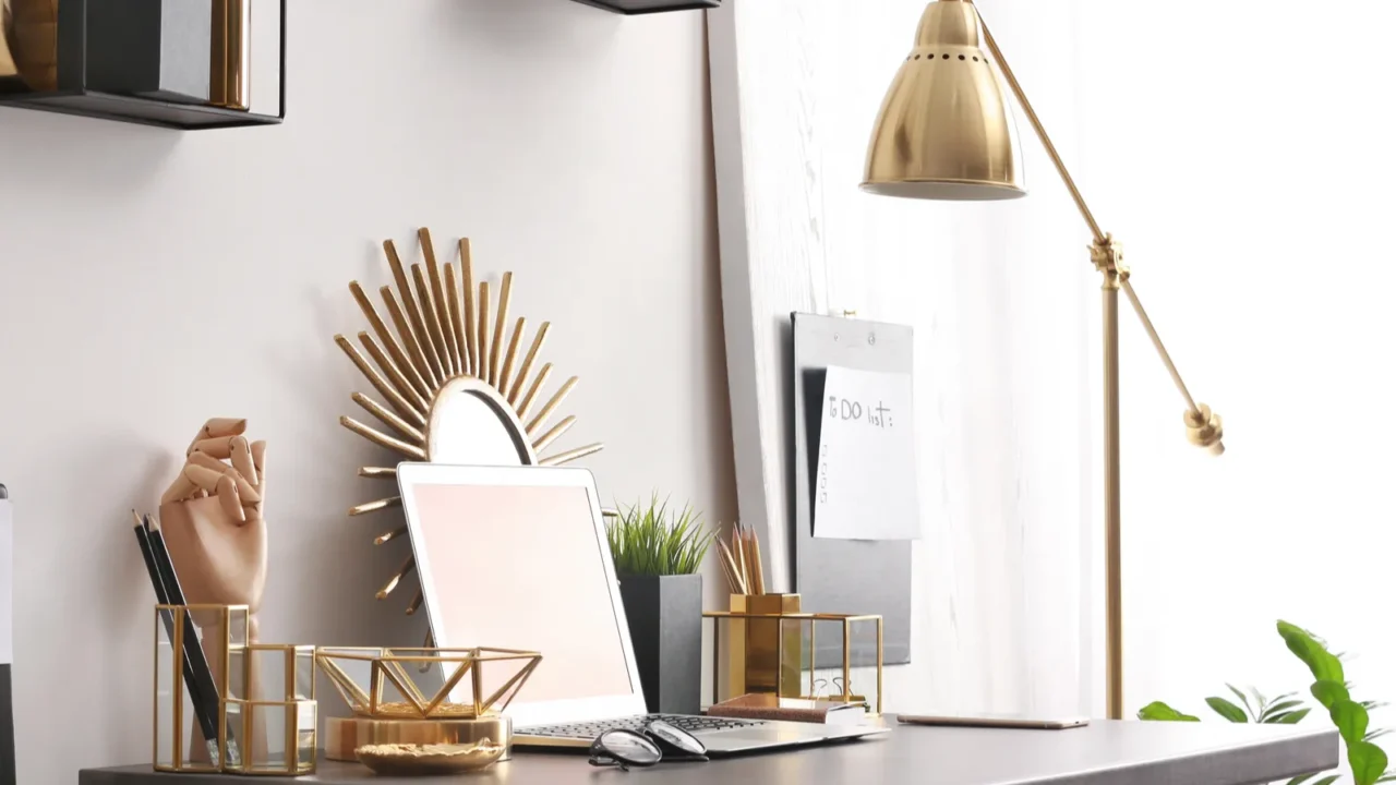 Modern workplace setup with laptop and golden decor accents near a window.