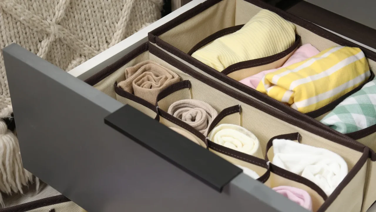 An open nightstand drawer with drawer organizer in it, holding neatly folded socks and t-shirts.