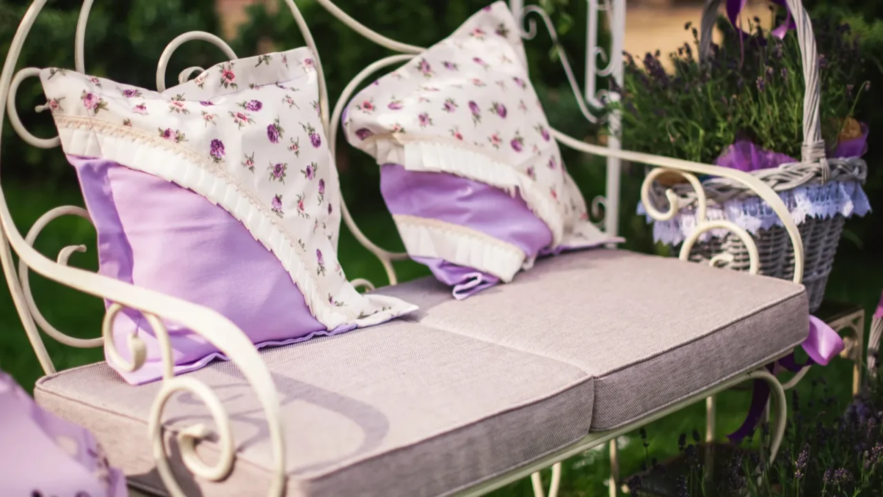 A metal bench with soft cushions and throw pillows on it.