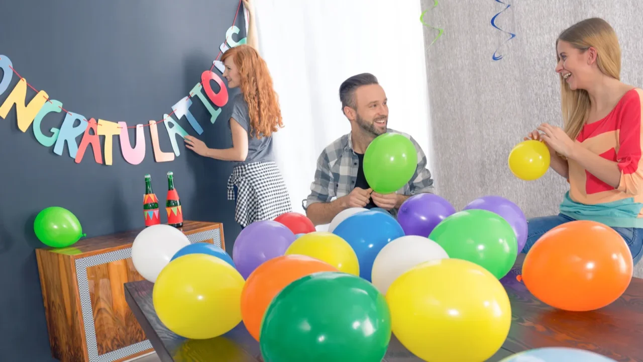 A happy family in a living room making the preparations for a grad party with buntings and balloons.