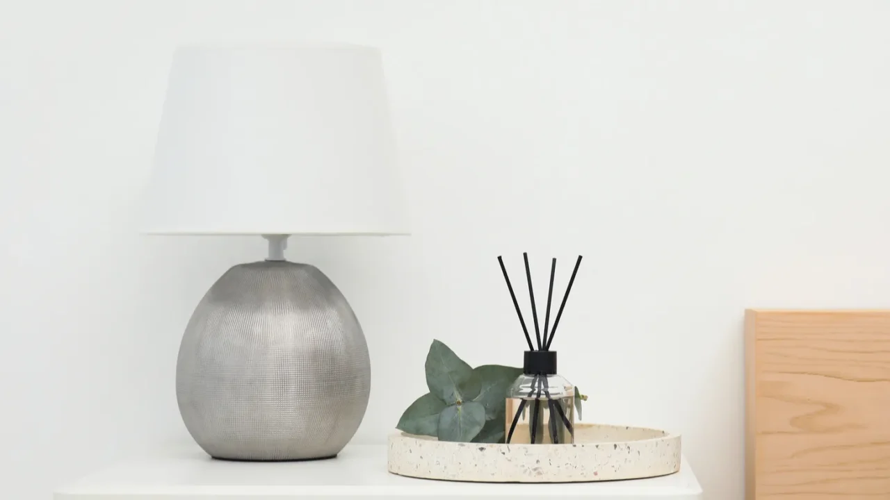 reed diffuser with lamp and eucalyptus on nightstand in bedroom
