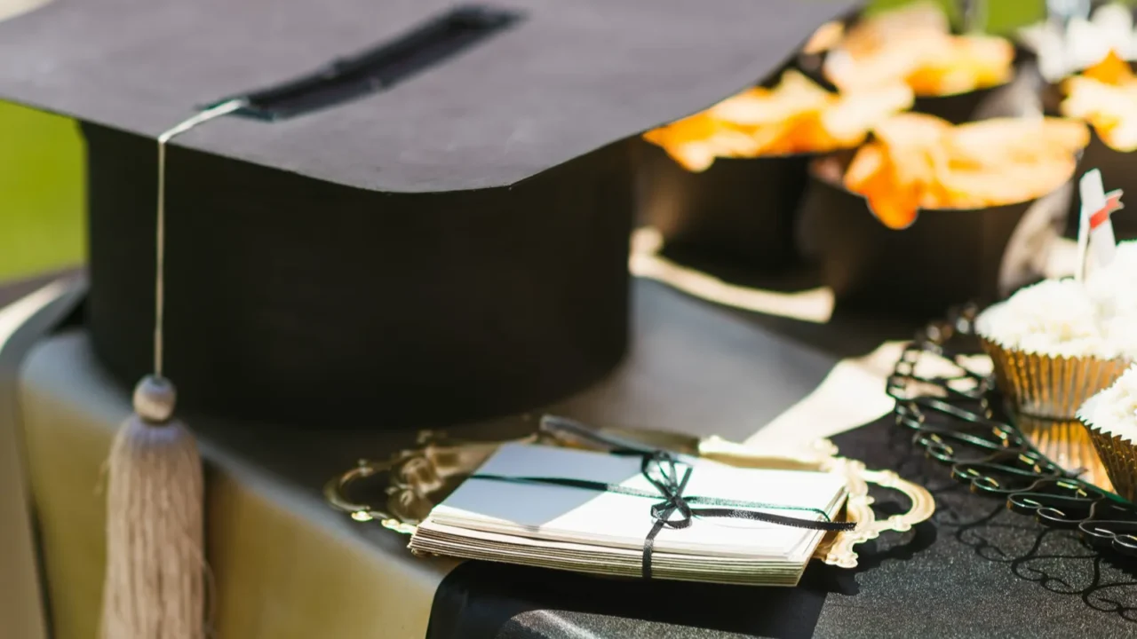 A graduation party table setting with graduation cap and cards placed on a table alongside food.