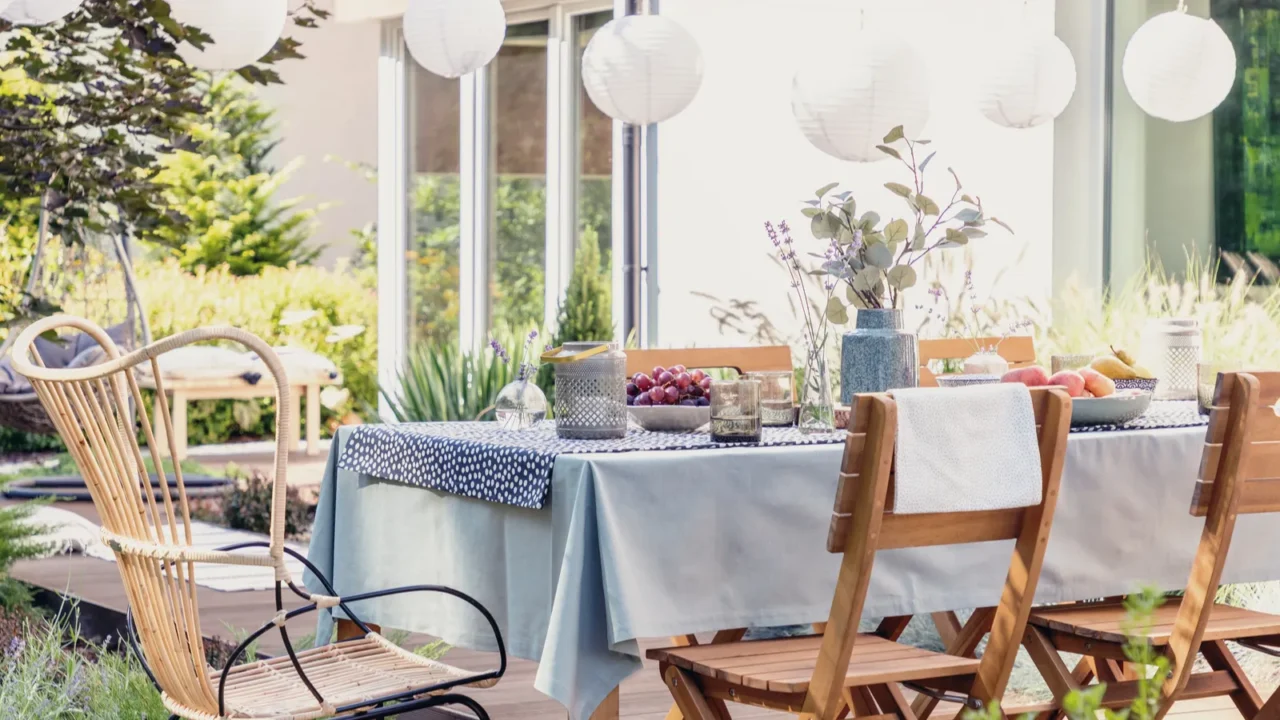 table with wooden chairs in bright green garden of modern