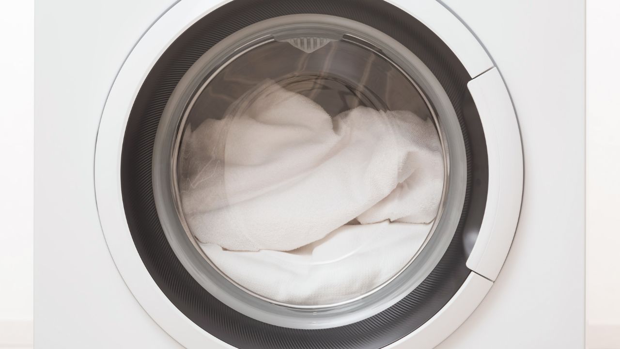 A front-loading washing machine with a white towel inside.