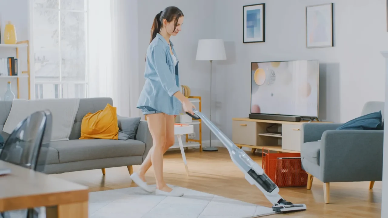A lady cleaning her living room with a cordless vacuum.