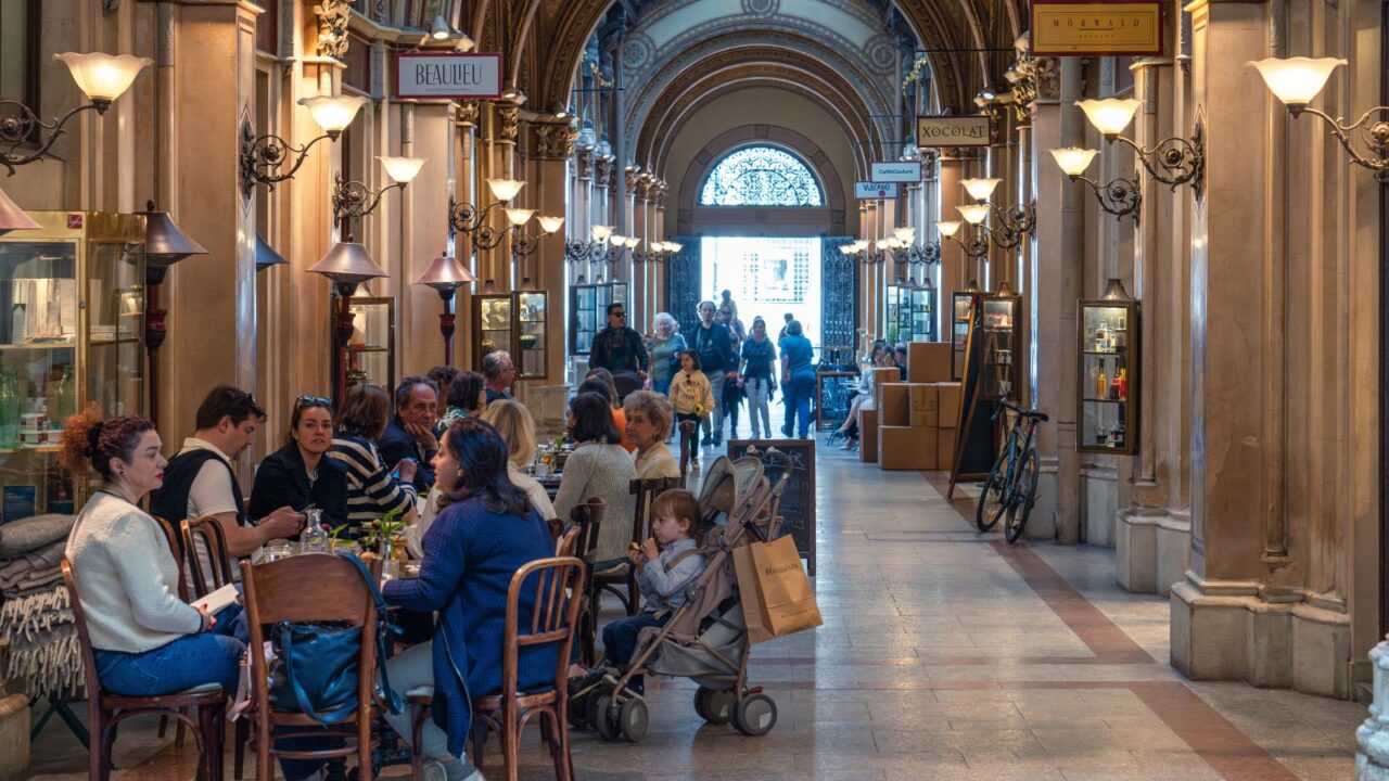 A bustling indoor shopping gallery with people sitting and walking.