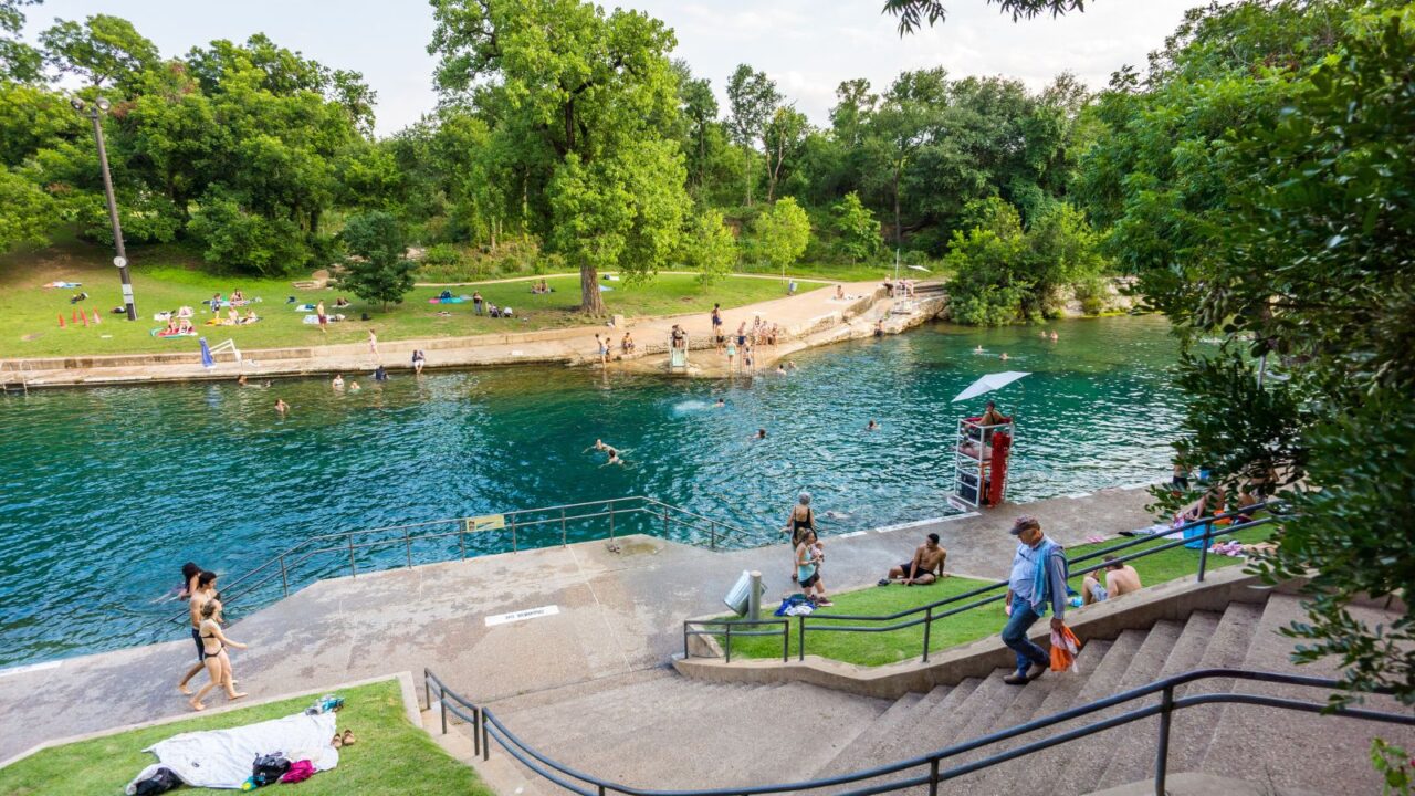Tourists and swimmers enjoy the cool natural water of Barton Springs pool in Austin, Texas.
