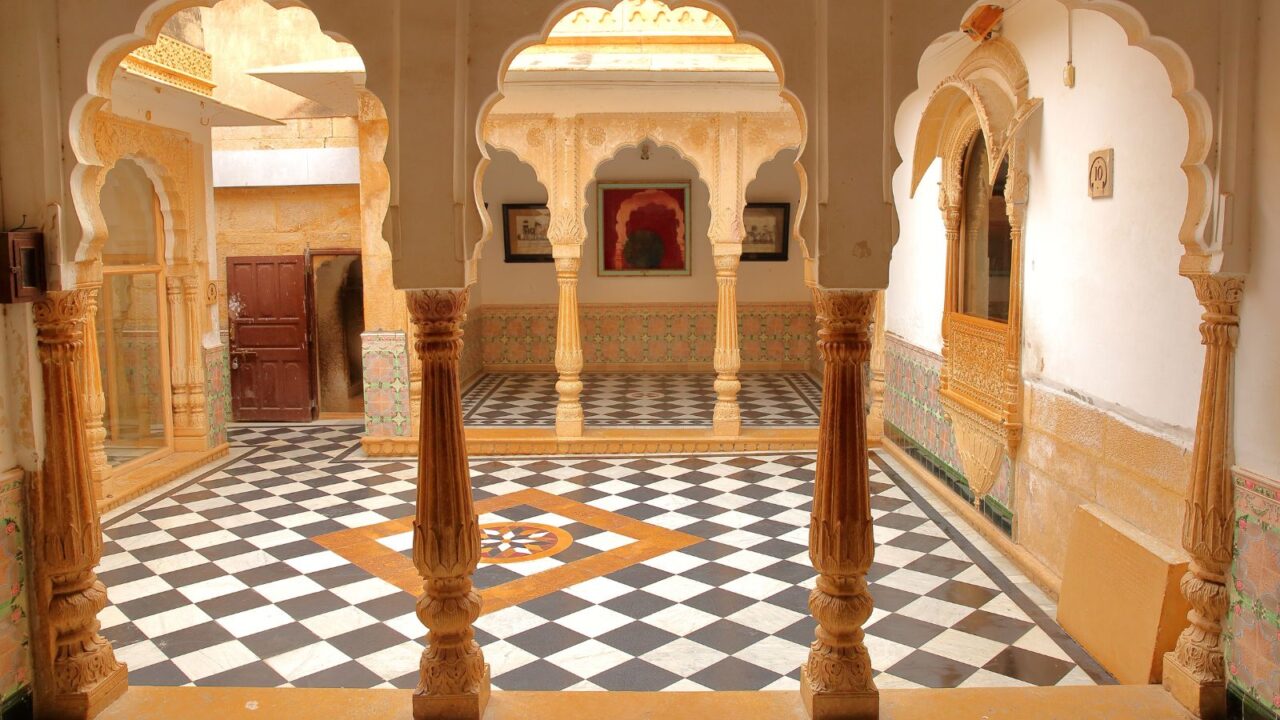 The interior of Jaisalmer Fort Palace wih arcades and patterned pavement.