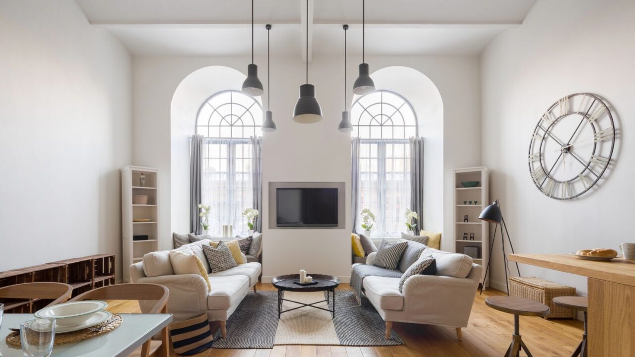 Cozy living room with white sofas, large windows, and modern decor.