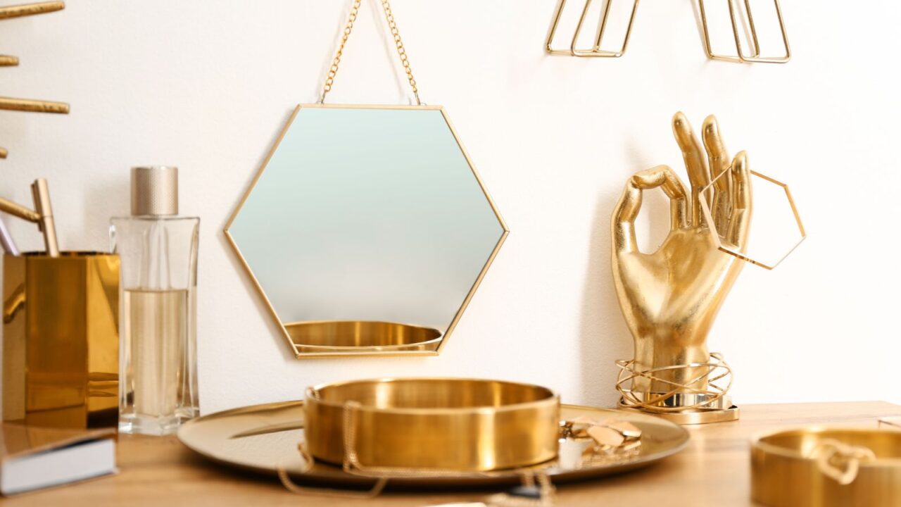 Composition with gold accessories on dressing table near white wall