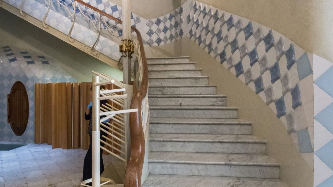 Interior staircase features smooth marble steps, a twisted wood-and-iron handrail, and walls adorned with glossy blue and white diamond-patterned ceramic tiles