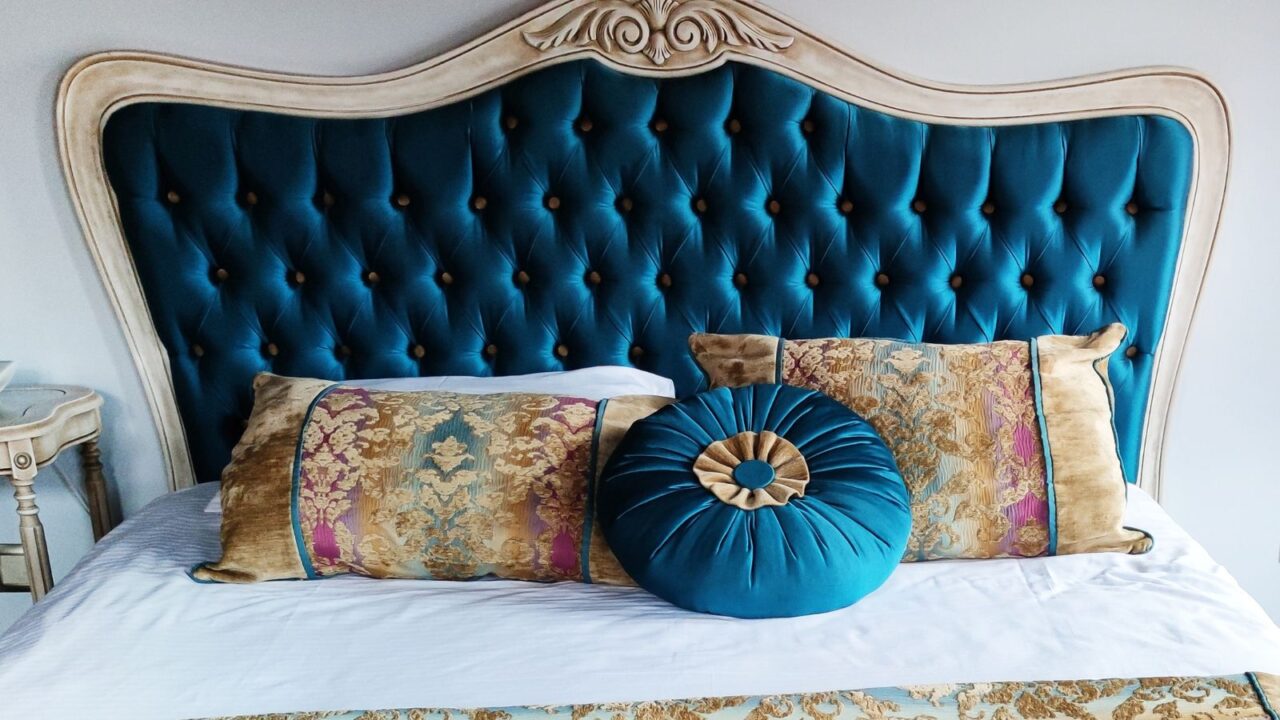 Elegant vintage style bed with headboard and decorative pillows.