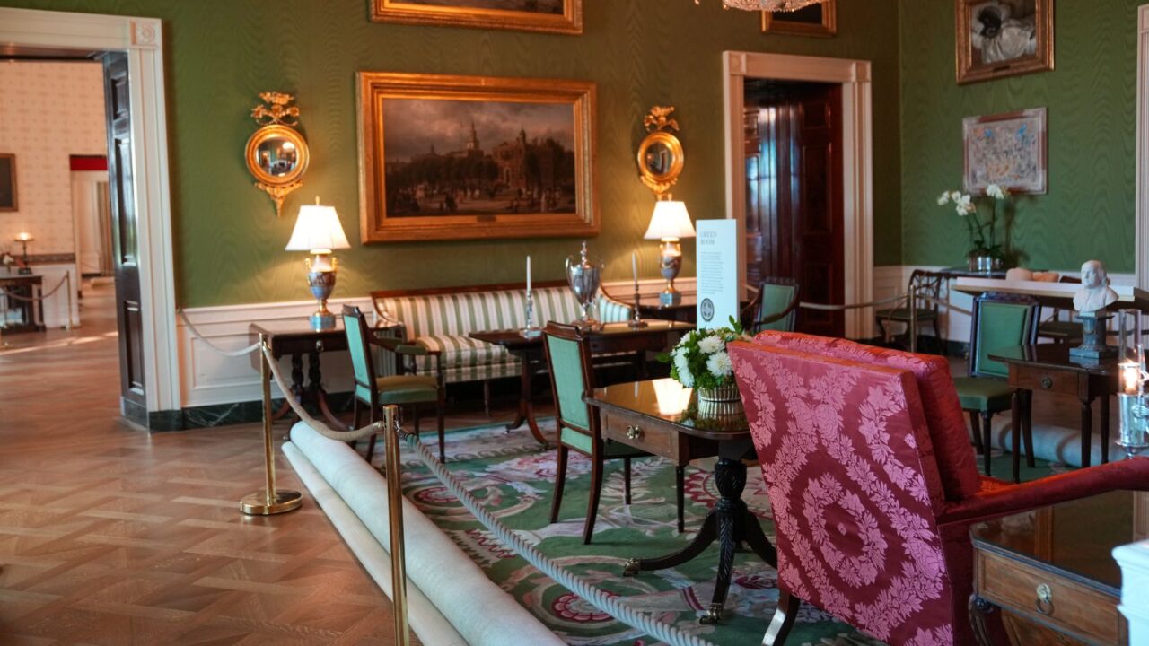 The Green Room of the White House, featuring Federal-style furniture including a sofa, chairs, and tables, with paintings and mirrors adorning the green walls