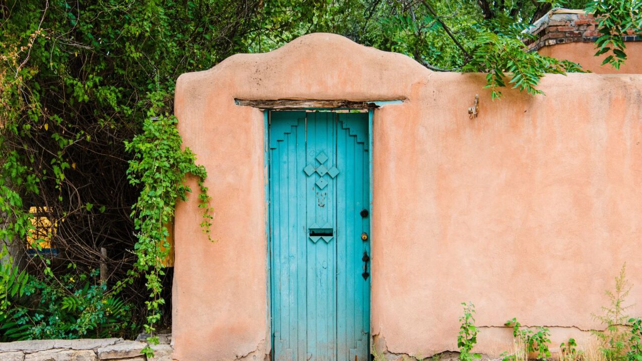 Wood turquoise colored door set in an old adobe wall in Santa Fe, New Mexico