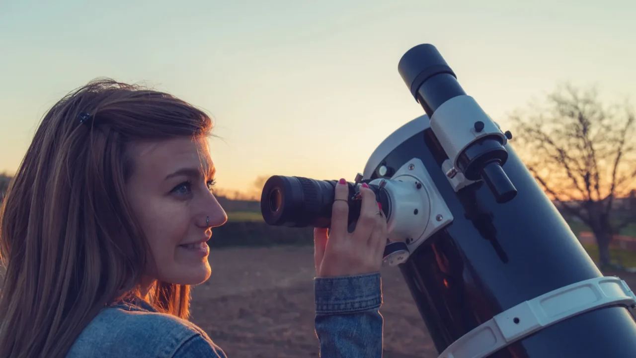 girl looking at the moon through a telescope