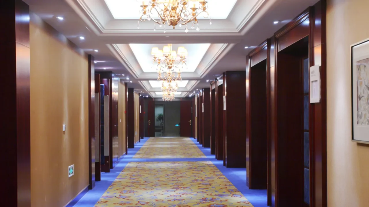 Hallway of a hotel with beautiful carpets and ornate chandeliers.