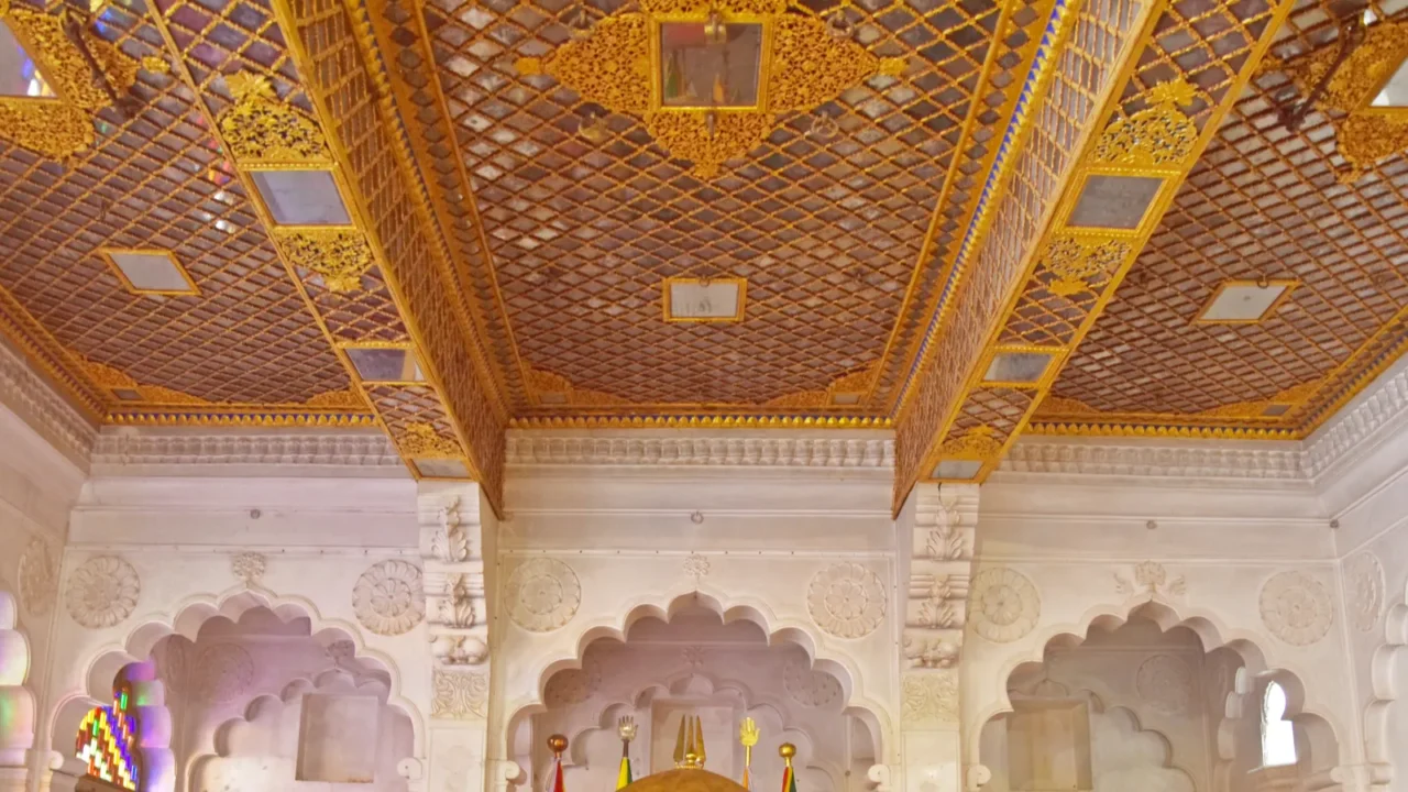 A grand Indian palace balcony with a richly decorated golden ceiling and detailed ceiling work.
