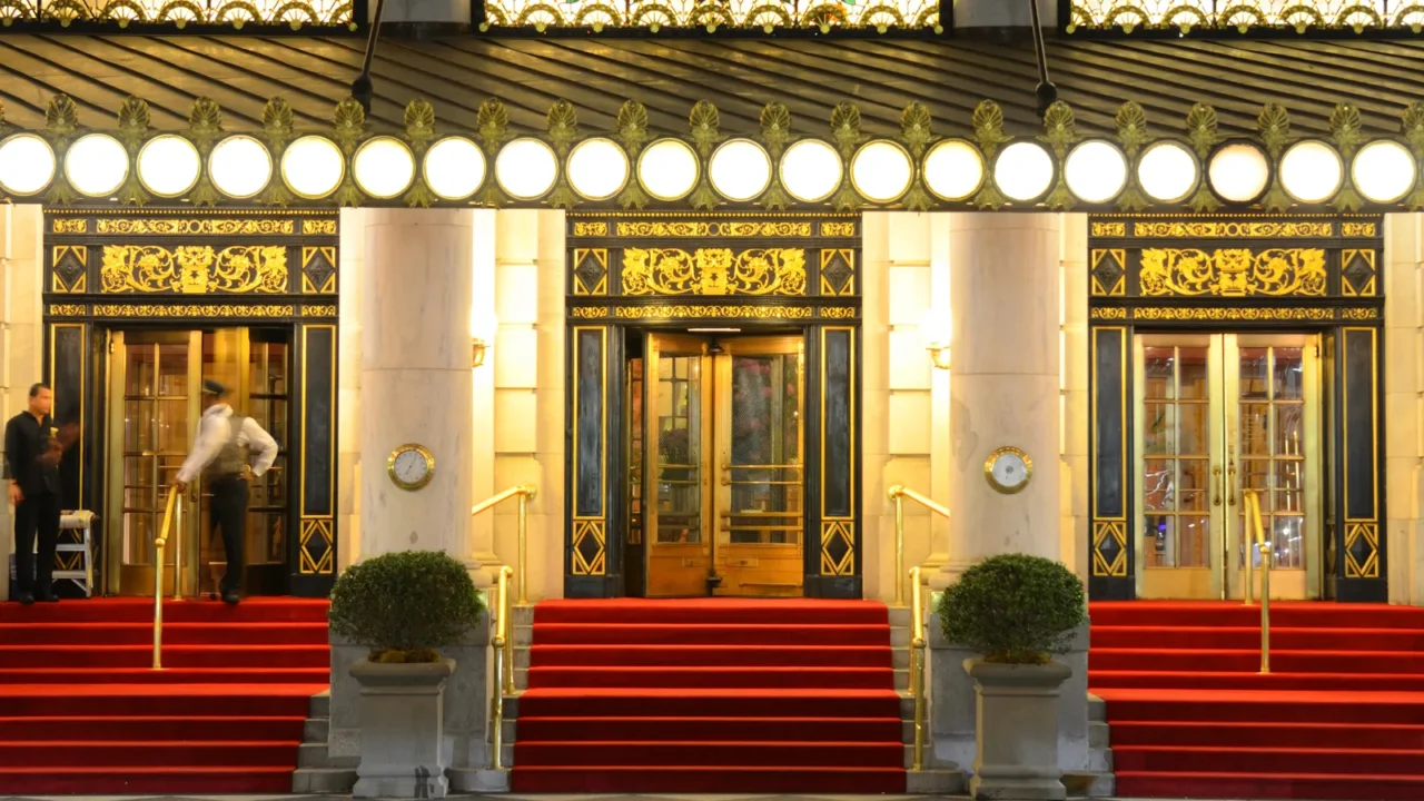 Entrance of the Plaza Hotel with its iconic red carpet and beautiful architectural details on the doors.