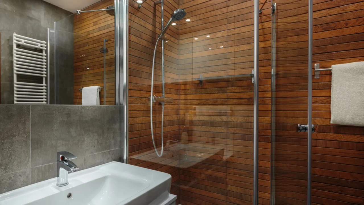 A modern bathroom with wood-paneled walls and a shower area.
