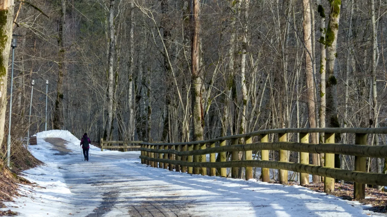 a man in dark clothing walking along a snowy path